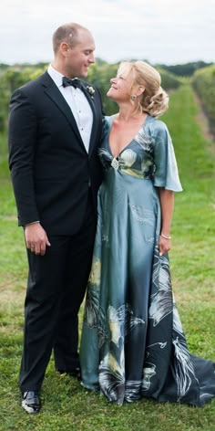 a man and woman in formal wear standing next to each other on a lush green field