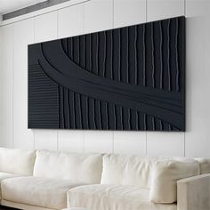 a living room with a white couch and black art piece on the wall above it