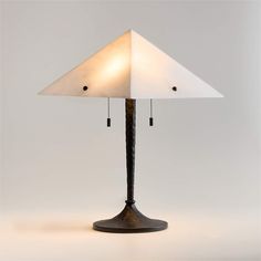 a lamp that is sitting on top of a wooden base and has a white shade over it