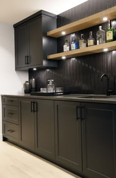 a kitchen with black cabinets and wooden shelves on the wall, along with an empty sink