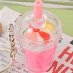 a small cup filled with candy sitting on top of a table next to a keychain