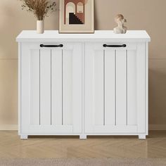 a white cabinet with two doors and some vases on top of it next to a wall