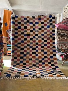 a large multicolored quilt on display in a room filled with rugs and other items