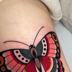 a colorful butterfly tattoo on the thigh