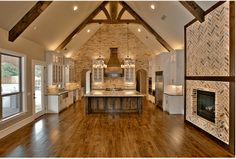 a large open kitchen with wood flooring and white cabinets in the middle of it