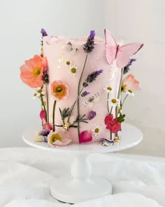 a pink cake decorated with flowers and butterflies