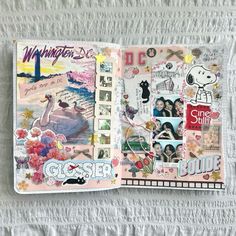 an open book with pictures and stickers on the pages is laying on a bed