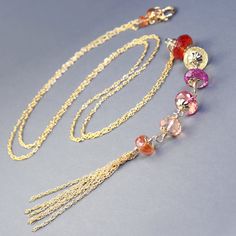 Delicate chain necklace featuring elaborate pendant created with colorful sapphire pendant. Large roundels of micro faceted orange, lemon yellow, pink, and peach sapphire, adorned with flower caps are wire wrapped into a long row further embellished with multi row chain tassel. This elegant necklace is 25inches long and pendant measure additional 5.75inches.  Perfect alone, beautiful paired with chain and other gemstone necklaces. Sapphire roundels from 8 to 10.5mm Thank you for looking! Please Fusion Style Faceted Bead Necklaces As Gift, Fusion Style Necklace With Faceted Beads As Gift, Fusion Style Necklace With Faceted Beads For Gift, Elegant Orange Jewelry With Chain, Faceted Lariat Necklaces For Jewelry Making, Gift Lariat Necklace With Faceted Beads, Fusion Style Faceted Necklace For Gift, Faceted Beads Lariat Necklace Gift, Elegant Orange Beaded Chain Jewelry