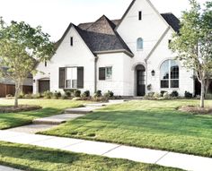 a white house with grass and trees in the front yard