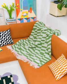 a living room with an orange couch and colorful throw pillows on the back of it