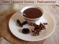 a white plate topped with chocolate and nuts next to a cup of hot chocolate on top of a saucer