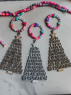 three necklaces with words written in different languages are on a marble surface, next to each other