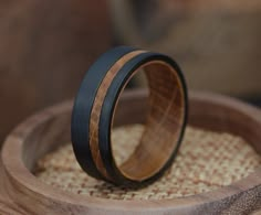 two wooden wedding bands sitting on top of a wooden box with woven material in the background