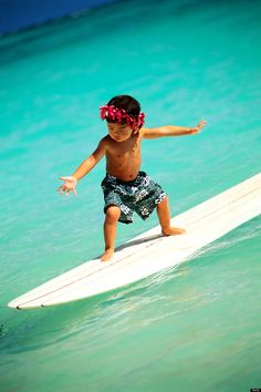 a small child on a surfboard in the ocean