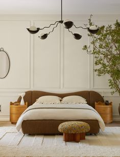 a bedroom with a bed, ottoman and plant