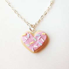 a pink heart shaped cookie with sprinkles is on a silver plated chain