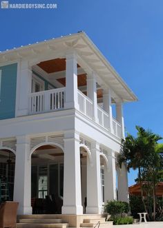 a large white house sitting on top of a lush green field next to palm trees