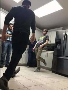 a group of people standing around in a kitchen