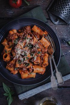 pasta with meat sauce and parmesan cheese in a black bowl on a wooden table