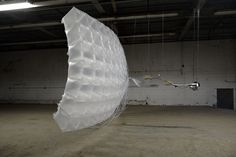 a large white object suspended from the ceiling in an empty room with no one around it