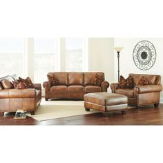 a living room filled with brown furniture on top of a hard wood floor