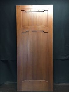 a wooden door is shown against a black wall with the bottom panel missing from it