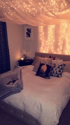 a bed with white sheets and lights hanging from the ceiling