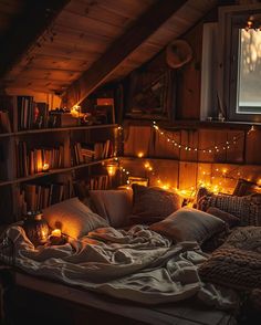 a bed with lots of pillows and blankets on top of it in a room filled with books