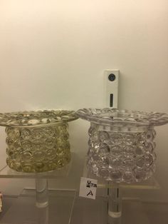 two glass bowls sitting on top of each other in front of a wall mounted device