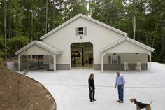 two people and a dog standing in front of a garage