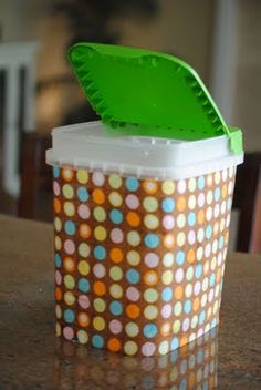 a plastic container sitting on top of a table with a green lid and polka dot design