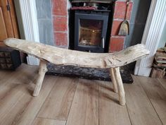 a wooden bench sitting in front of a fire place on a hard wood floor next to a fireplace