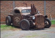 an old rusted truck parked in front of a brick wall