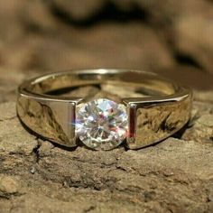 a close up of a ring with a diamond in it on top of a rock