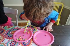 a young boy blowing out candles on his birthday cake with pink plates and colorful napkins