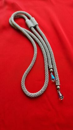 a silver and blue leash on a red cloth with a metal hook in the middle