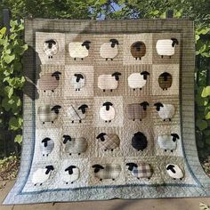 a quilt with sheep on it sitting in front of some trees