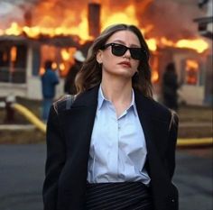 a woman wearing sunglasses standing in front of a fire