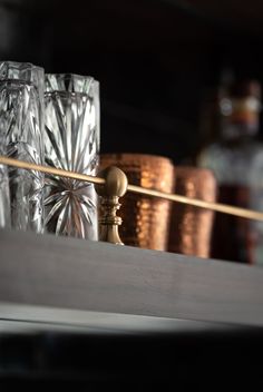 some glasses are sitting on a shelf with copper and silver cups in the foreground