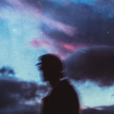 a man standing in front of a cloudy sky