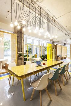 a long table with many chairs around it in a large room that has yellow doors and windows