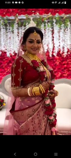 a woman in a red and gold bridal outfit standing next to a white couch