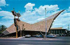 an old photo of a building with cars parked in front