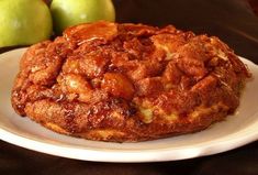 an apple pie on a white plate next to two green apples