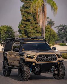 a tan truck is parked in the parking lot with palm trees and buildings behind it