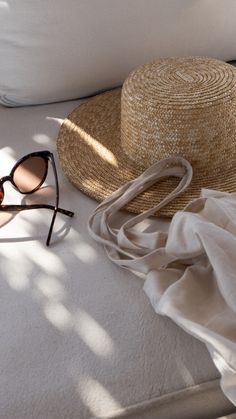 a straw hat, sunglasses and a white sheet on the floor next to a pillow