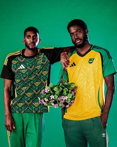 two men standing next to each other in front of a green background wearing matching jerseys