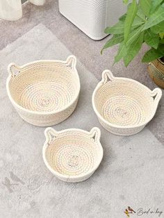 three woven baskets sitting on the ground next to a potted plant