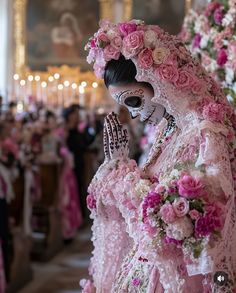 a woman dressed in pink and white holding her hand up to her face while wearing a skeleton mask