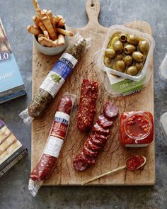 an assortment of meats and vegetables are on a cutting board next to other foods